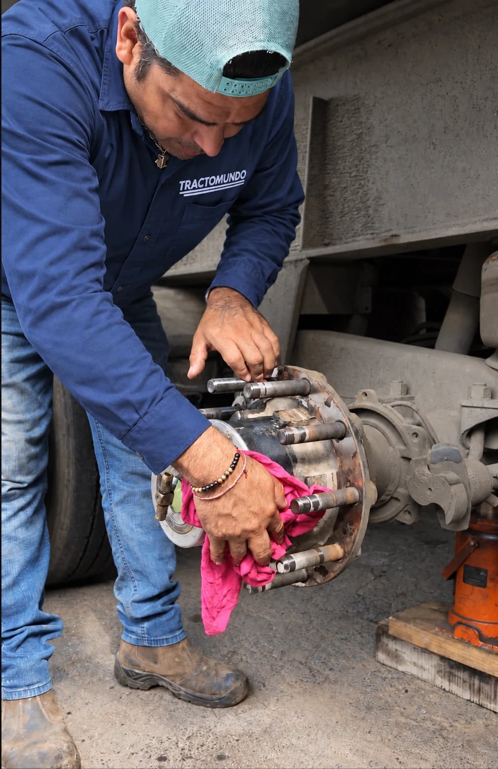 Mecánico trabajando en el conjunto de rueda de una unidad; fotografía retocada con uniforme Tractomundo